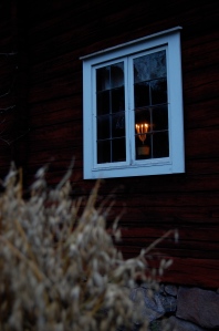 Levande ljus i fönstret i ett gammalt falurött hus